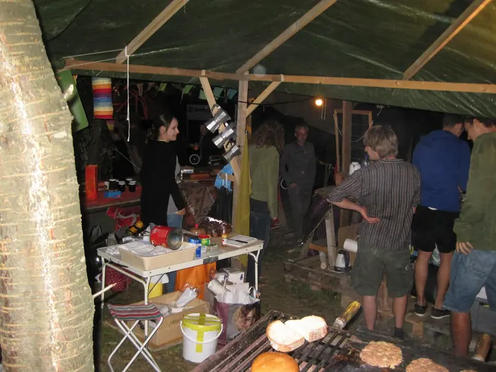 Helfer arbeiten nachts in der beleuchteten Festivalküche.