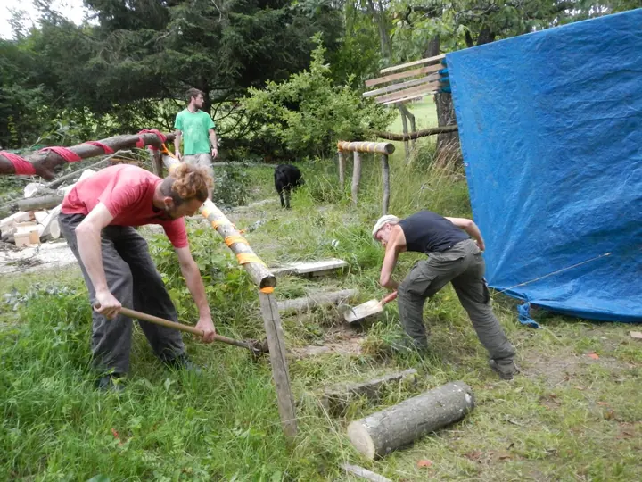 Mehrere Personen arbeiten mit Werkzeugen am Boden der Festivalwiese.