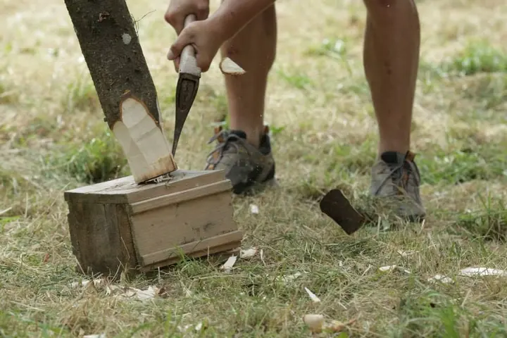 Eine Person spaltet mit einer Axt Holz auf der Festivalwiese.