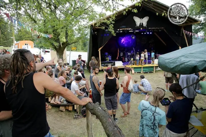 Festivalgäste schauen am Tag zur kleinen Bühne zwischen Bäumen.