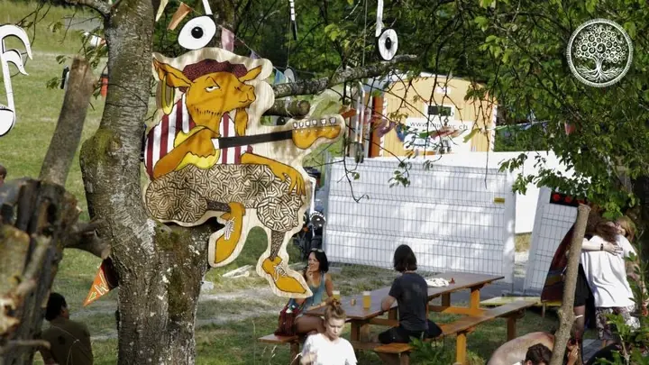 Bunte Tierfiguren und Dekoration hängen in einem Baum über dem Gelände.