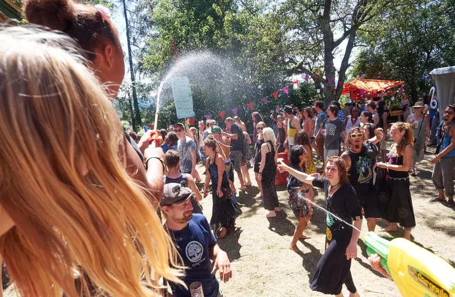 Festivalgäste tanzen an einem sonnigen Nachmittag im Wassernebel.
