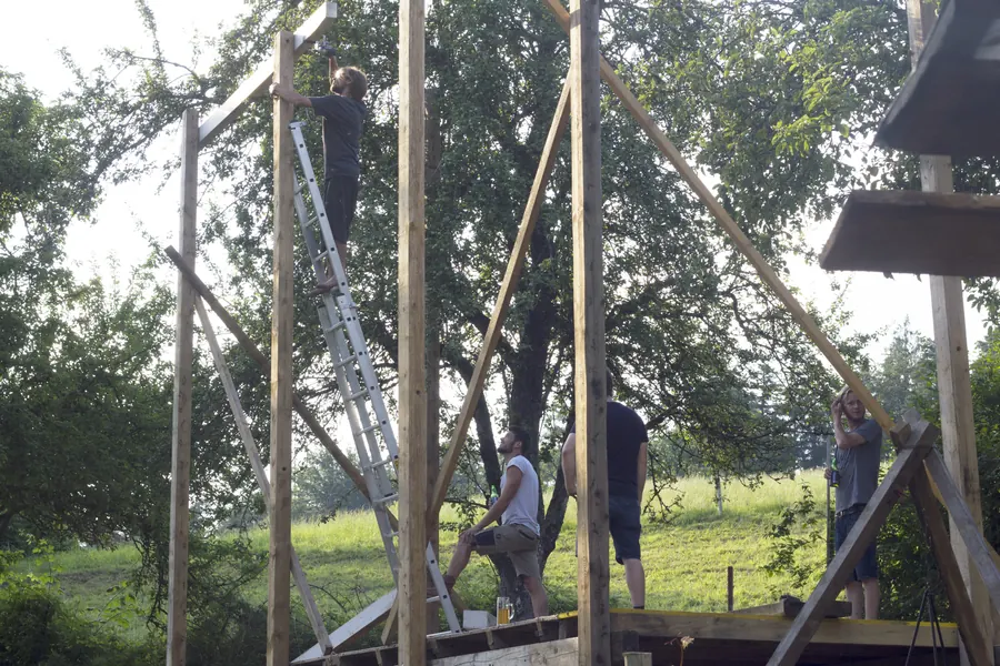 Freiwillige errichten eine hohe Holzkonstruktion auf der Festivalwiese.