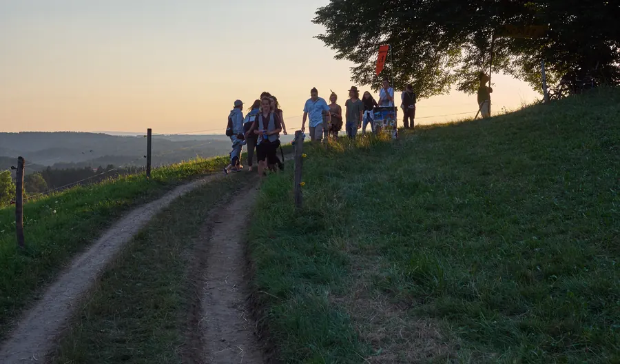 Eine Gruppe geht bei Sonnenuntergang einen Feldweg auf dem Hulmen entlang.
