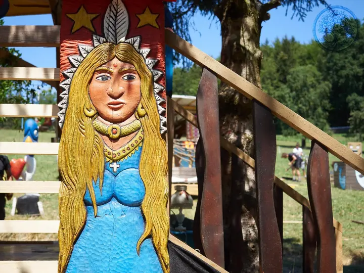Eine bemalte Frauenfigur schmückt ein hölzernes Treppengeländer.
