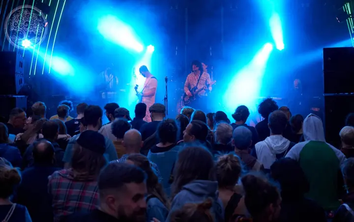 Publikum steht vor einer blau beleuchteten Bühne beim Openair 2019.