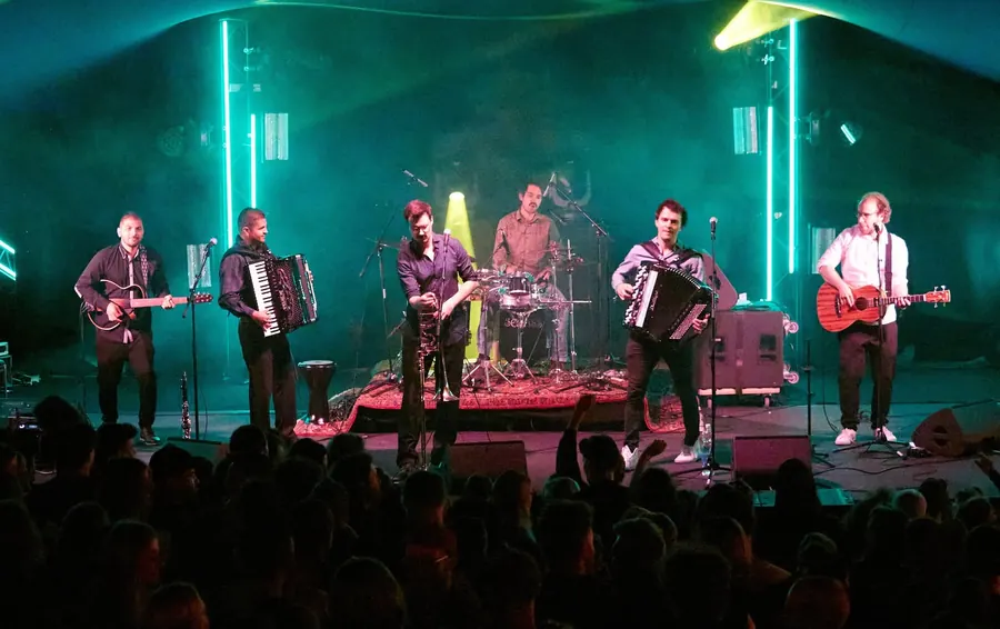 Eine grosse Band spielt im grünen Bühnenlicht.