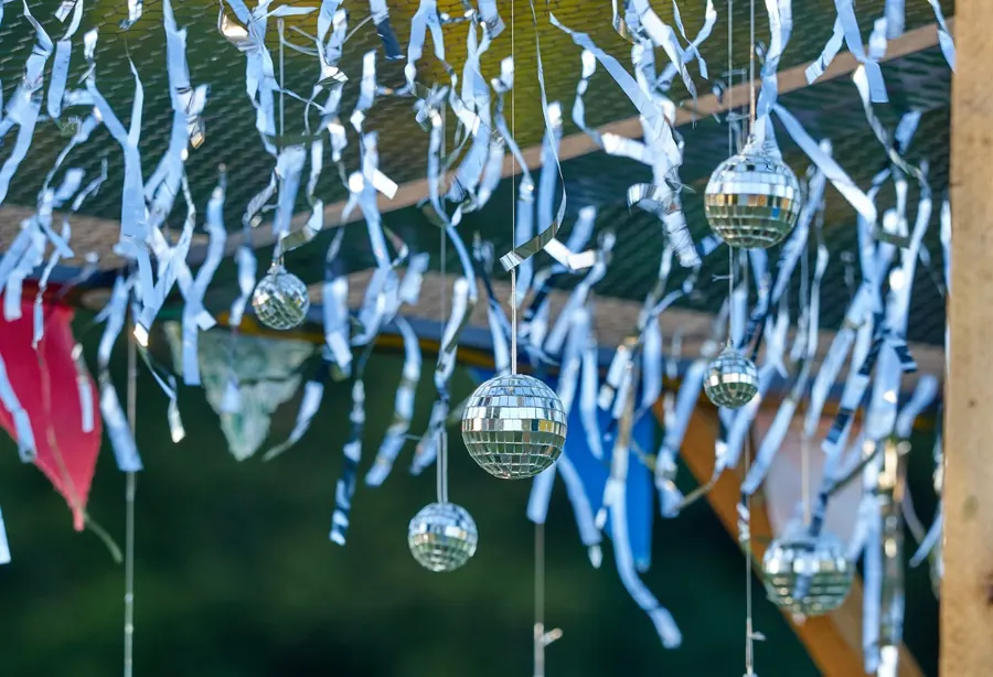 Bänder und kleine Discokugeln hängen als Dekoration zwischen den Bäumen.