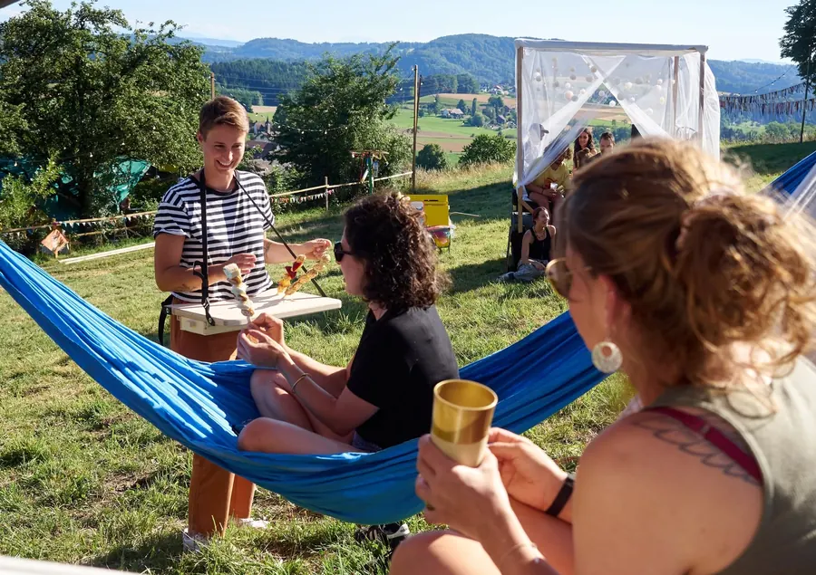 Festivalgäste entspannen in einer Hängematte mit Blick über die Landschaft.