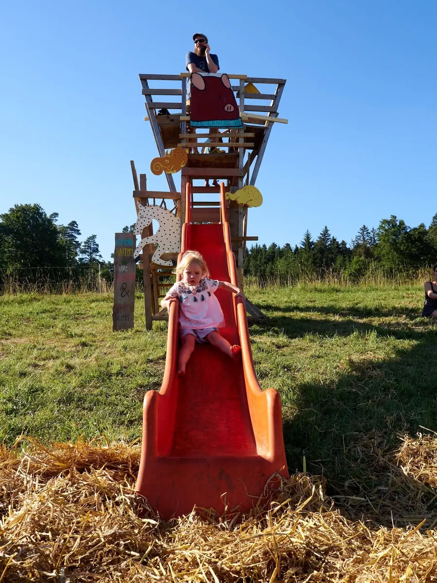 Ein Kind rutscht auf der grossen roten Holzrutsche.