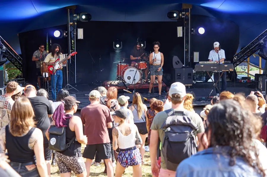 Publikum steht vor der Bühne bei einem Konzert am sonnigen Nachmittag.
