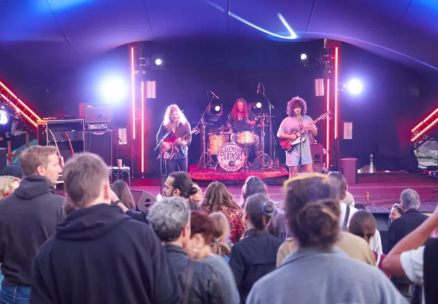 Publikum steht vor einer beleuchteten Rockbühne am Abend.